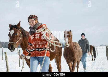 Jeune couple en train de marcher avec les chevaux dans le champ, Bavière, Allemagne Banque D'Images