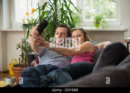 Couple fighting for remote dans la salle de séjour, Munich, Bavière, Allemagne Banque D'Images