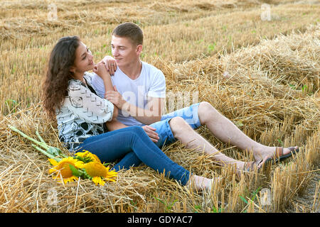 Happy young couple assis dans wheaten field au soir, romantique personnes concept, beau paysage, saison d'été Banque D'Images