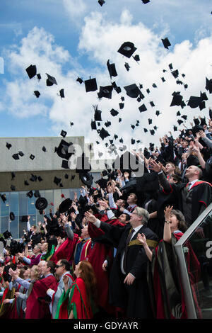 L'enseignement supérieur au Royaume-Uni : les étudiants de l'université d'Aberystwyth portant des robes traditionnelles, capes et bouchons jeter leurs cartes de mortier dans l'air de la manière traditionnelle fête leur diplôme lors de la cérémonie du jour, Juillet 2016 Banque D'Images