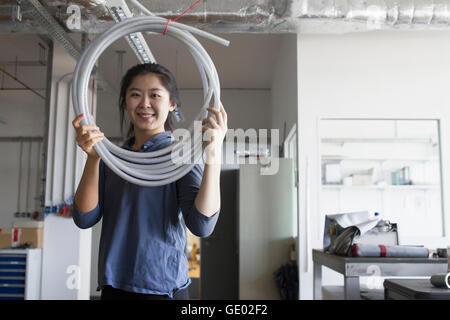 Jeune femme ingénieur avec tuyau dans une installation industrielle, Freiburg im Breisgau, Bade-Wurtemberg, Allemagne Banque D'Images