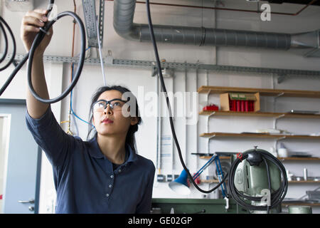 Jeune ingénieur féminin contrôle de câbles dans une installation industrielle, Freiburg im Breisgau, Bade-Wurtemberg, Allemagne Banque D'Images