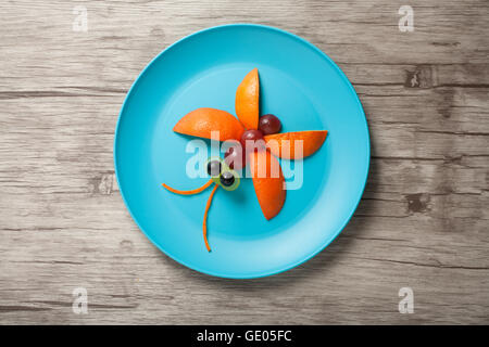 Butterfly formés de fruits dans une assiette et fond de bois Banque D'Images