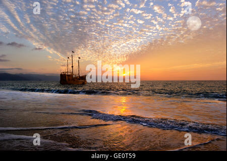 Bateau de pirate lune est un vieux navire antique en mer avec drapeaux au vent comme le soleil se couche à l'horizon de l'océan et la pleine lune Banque D'Images