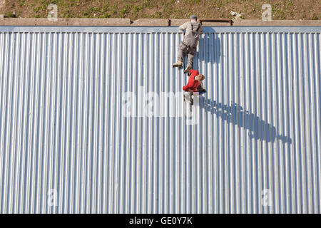 Szczecin, Pologne - 07 Avril 2016 : Les travailleurs de la réparation d'un store toiture en feuilles de métal ondulé, photo prise d'en haut. Banque D'Images