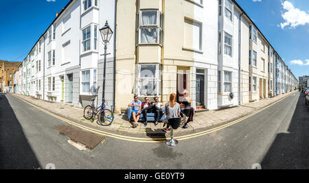 Les jeunes gens assis dans la rue devant leur maison sur un après-midi d'été à Brighton. Banque D'Images