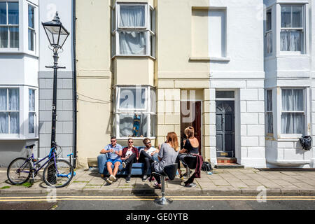 Les jeunes gens assis dans la rue devant leur maison sur un après-midi d'été à Brighton. Banque D'Images