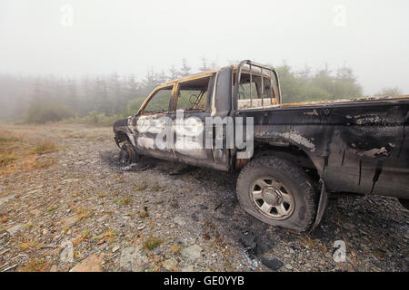 Burnt Out chariot abandonnées sur un terrain commun. Vue sur le côté à l'avant Banque D'Images