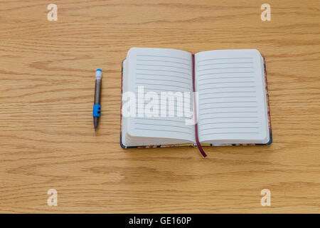 Un pencile à côté d'un ordinateur portable avec des pages vierges sur une table. Banque D'Images