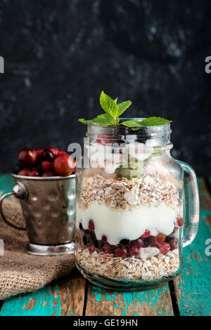 Muesli, yaourt et fruits frais dans le verre pot Mason sur table en bois. Petit-déjeuner sain composé de muesli Banque D'Images