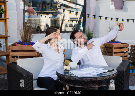 Happy business couple at outdoor restaurant selfies Banque D'Images