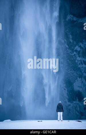 Femme debout en face de cascade Skogafoss, Islande Banque D'Images