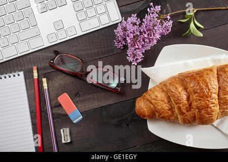 Vue supérieure de travail de bureau - clavier, crayon, verres, croissant et portable sur tableau noir Banque D'Images