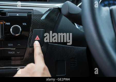 Libre de jeune femme en appuyant sur le bouton d'urgence sur le sport voiture tableau de bord. Banque D'Images