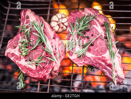 Faux-filets de boeuf et grill avec un feu brûlant derrière eux. Banque D'Images