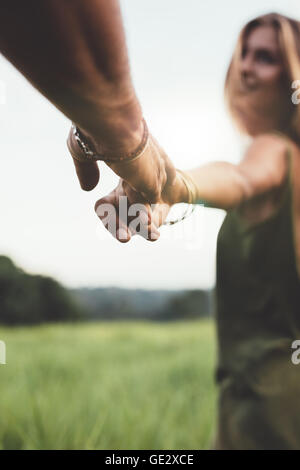 Gros plan de l'homme tenant la main de sa petite amie dans la pelouse. Shot POV de couple dans la nature. Banque D'Images