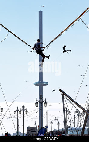 Brighton Sussex UK 23 Juillet 2016 - Un jeune homme jouit d'une ride sur le front de saut dans le contexte de la British Airways j360 tour d'observation que des milliers affluent à la plage de Brighton que le soleil sort finalement après une matinée de Misty météo . La tour i360 est en raison d'ouvrir au public le 4 août cette année Crédit : Simon Dack/Alamy Live News Banque D'Images