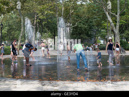 Les adultes et les enfants jouer dans l'eau des fontaines dans Battery Park, New York, pour se rafraîchir pendant une vague de chaleur. Banque D'Images