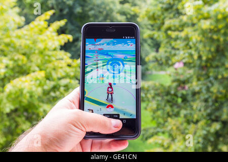 Apple iPhone6 Plus tenu dans une main montrant son écran avec Pokemon Rendez-application. Banque D'Images