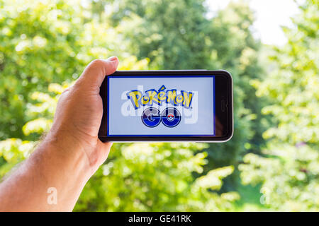 Apple iPhone6 Plus tenu dans une main montrant son écran avec Pokemon Rendez-application. Banque D'Images