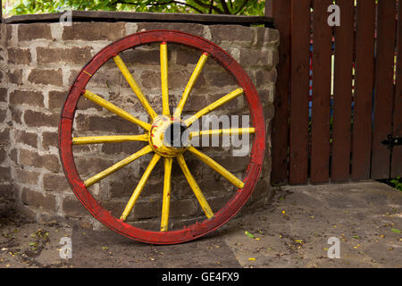 Vieille roue de chariot avec bord métallique s'appuyant sur un mur de pierre Banque D'Images