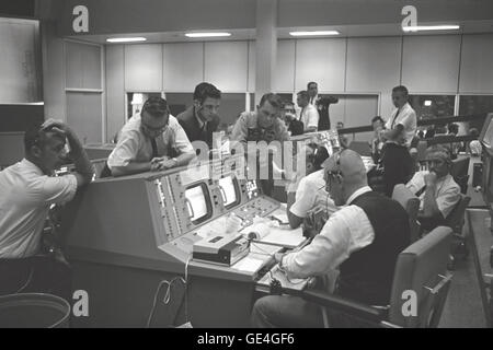 Vue sur les directeurs de vol console dans le centre de contrôle de mission (MCC), Houston, Texas, au cours de la vol Gemini 5. Assis à la console sont Eugene F. Kranz (premier plan) et le Dr Christopher C. Kraft Jr. (arrière-plan). Debout devant la console sont le Dr Charles Berry (à gauche), un homme non identifié dans le centre et M. Elliot astronaute Voir. Image #  : S65-28689 Banque D'Images