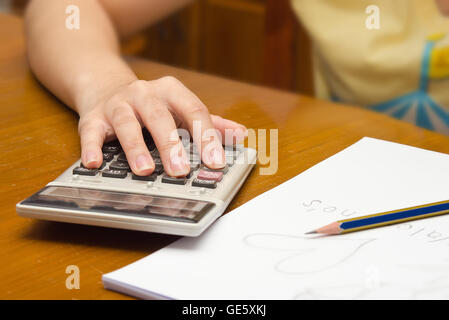 Notes et une femme calcule numéro sur la carte note calculatrice avec en arrière-plan Banque D'Images