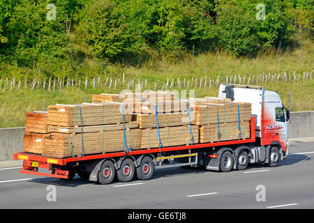 Les matériaux de construction de la chaîne logistique de transport par camions et remorques de poids lourds chargés de conduire le long du bois français d'autoroute Banque D'Images