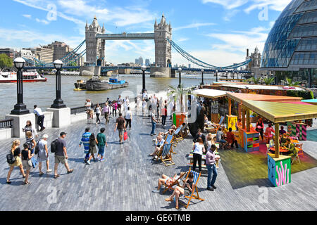 Les touristes et les employés de bureau déjeunent dans des stands de restauration rapide installés en été, dans des en-cas en plein air sur des chaises longues à côté de la Tamise, à Southwark, au Royaume-Uni Banque D'Images