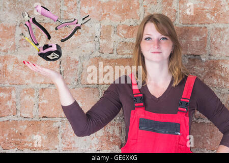 Jeune femme vêtu de rouge dans l'ensemble est debout devant un vieux mur de briques. La femme est à la recherche de l'appareil photo. Banque D'Images