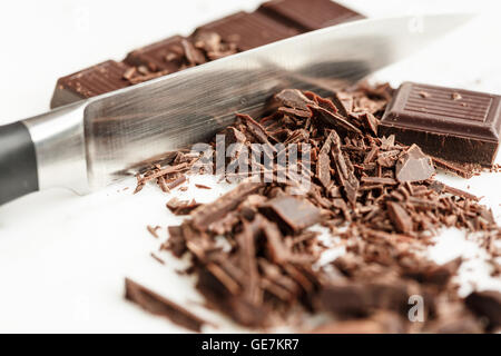Barre de chocolat et de copeaux avec un couteau sur fond blanc Banque D'Images