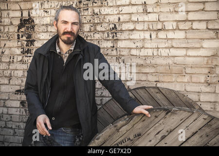 Outdoor portrait of young Asian Man in Black au mur de brique gris grungy urban background Banque D'Images