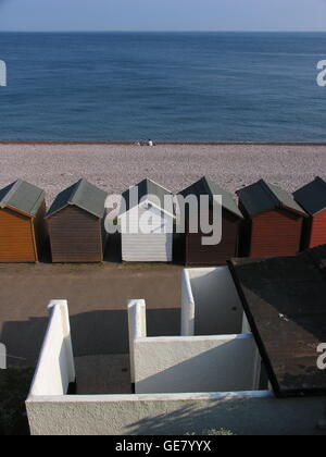 Juxtaposition de murs, cabines de plage, la plage de galets et de la mer, avec deux chiffres sur la plage à Budleigh Salterton. Banque D'Images