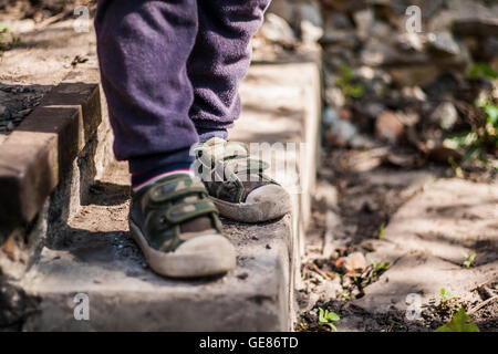 Les jambes de l'enfant dans sneakers sur l'escalier. Banque D'Images