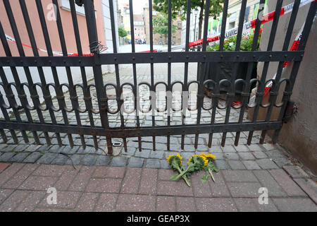 Ansbach, Allemagne. Le 25 juillet, 2016. Le tournesol se trouvent par une porte fermée derrière bande de police près de la scène de crime dans la vieille ville d'Ansbach, Allemagne, 25 juillet 2016. 15 personnes ont été blessées lors d'une attaque à motivation islamiste prétendument le 24 juillet 2016. L'auteur présumé, un homme de 27 ans pour les réfugiés en provenance de Syrie, a été tué dans l'attaque. Photo : Karl Josef OPIM/dpa/Alamy Live News Banque D'Images