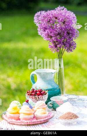 De délicieux petits gâteaux, de cerise et de pot sur la table dans le jardin Banque D'Images