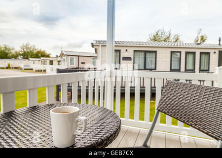 Vue d'un grand nombre de caravanes statiques à partir d'une véranda avec une tasse de thé sur une table à l'avant-plan à Presthaven Sands Holiday Park. Banque D'Images