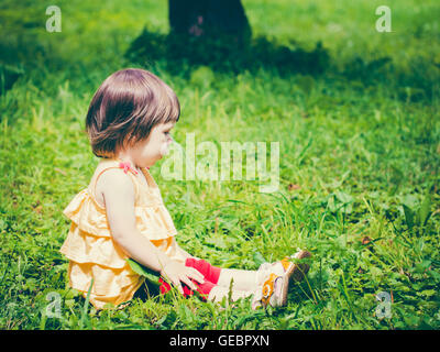 Un an baby girl sitting on grass et à l'écart Banque D'Images