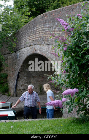 Deux personnes voile un bateau étroit sous un pont à northamptonshire braunston england uk Banque D'Images