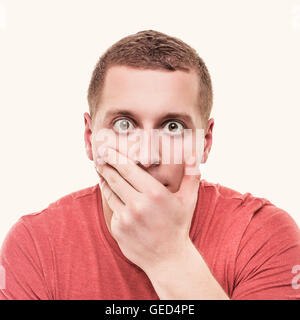 Homme choqué couvre sa bouche sur un fond blanc. Tonique photo. Banque D'Images