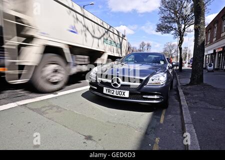 Mercedes SLK roadster stationné sur une rue de la ville avec une benne de camion passé Banque D'Images