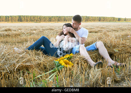 Happy young couple assis dans wheaten field au soir, romantique personnes concept, beau paysage, saison d'été Banque D'Images