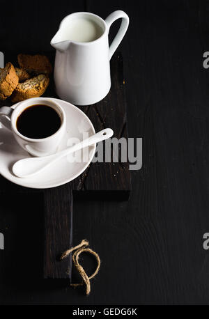 Tasse d'expresso chaud, crème de lait et de cookies sur rustique en bois sombre sur fond noir, copy space Banque D'Images