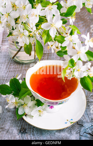 Tasse de thé sur la table de bois et Apple Blossom. L'heure du thé concept. Petit-déjeuner tasse de thé servi avec des fleurs. Banque D'Images