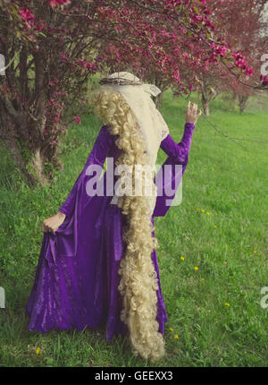 Jeune femme habillée en velours violet Raiponce portant des costumes médiévaux avec de longs cheveux blonds. Banque D'Images