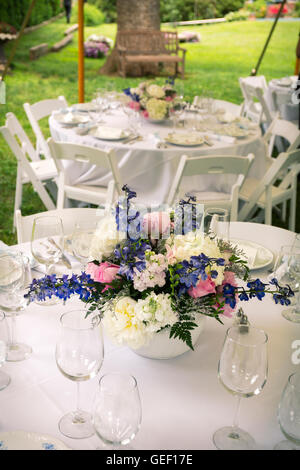 Les arrangements de fleurs sur les tables avec des lunettes nappe blanche. Banque D'Images