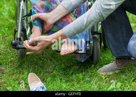 Aider l'homme femme handicapée sur fauteuil roulant Banque D'Images