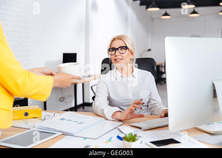 Secrétaire ou collègue de travail apportant une tasse de café de bienvenue pour le patron souriant Banque D'Images