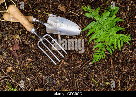 La truelle à la main et la fourchette portant sur compost de jardin Banque D'Images