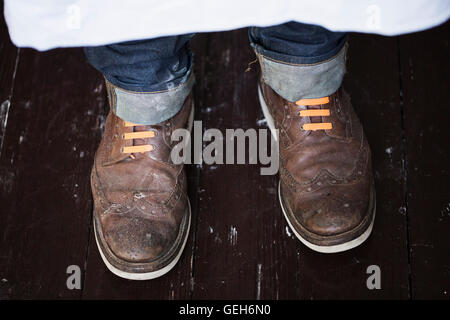 Close up of a man's pieds, portant des chaussures marron avec des lacets orange. Banque D'Images